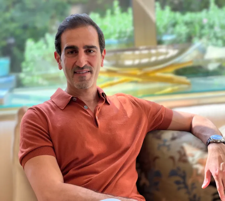 Majd Abu Zant cofounder of Ovasave  in an orange shirt sitting on a couch.